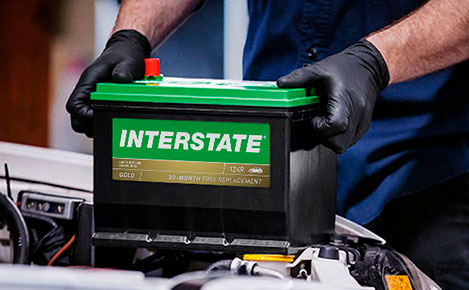 Tech installing an Interstate battery into the hood of a car