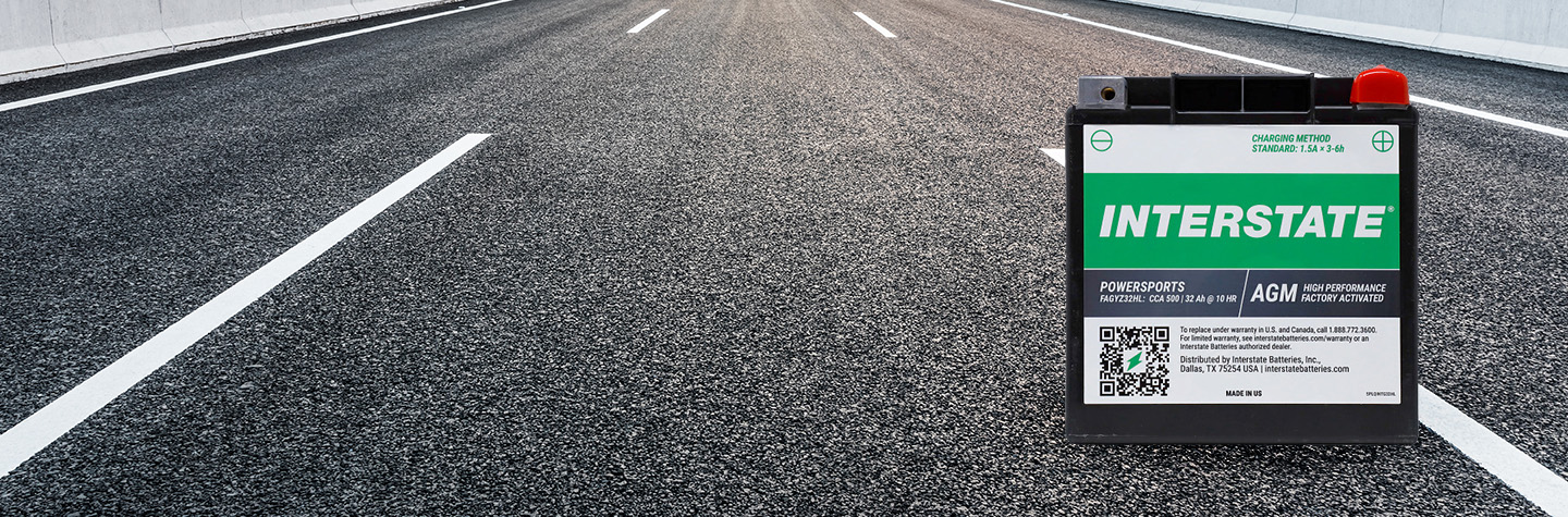 Interstate factory-activated AGM powersports battery on open paved highway with lane markings stretching into the distance