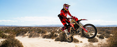 biker on a motorbike in mid-air in desert terrain