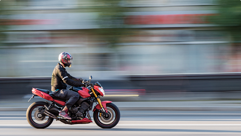 Person driving motorcycle on street in motion