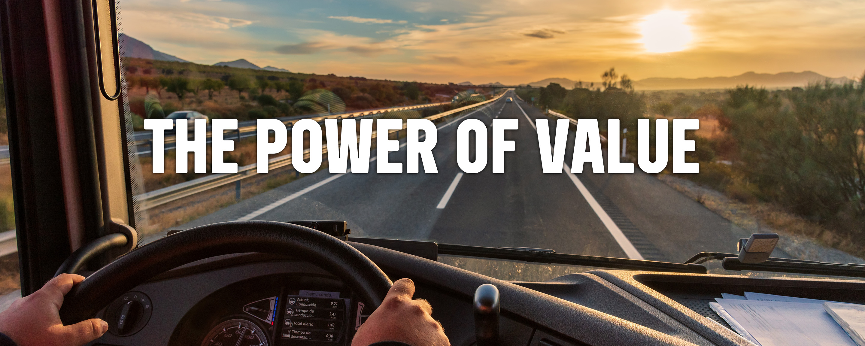 driver's hands on steering wheel with "The Power of Value" in windshield