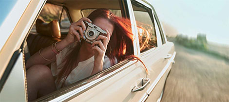 Niña conduciendo en un automóvil tomando una foto con una cámara digital