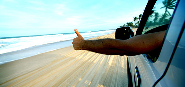 Person driving on beach with thumbs up out the window
