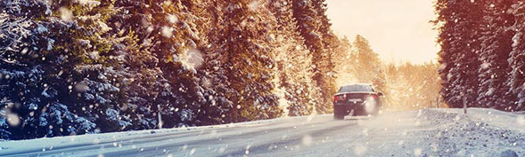 Car driving down snowy road